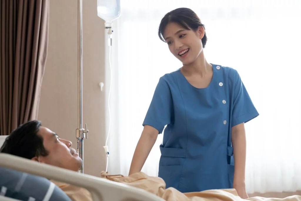 Asian nurse talking with patient in ward at hospital