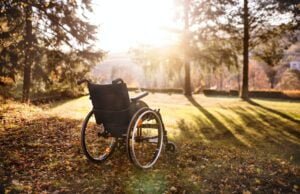 Empty wheelchair on a grass in park at sunset