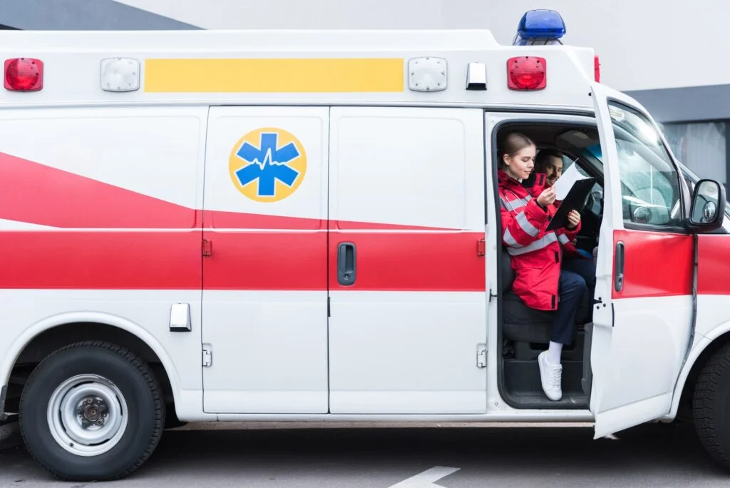 young male and female paramedics sitting in ambulance