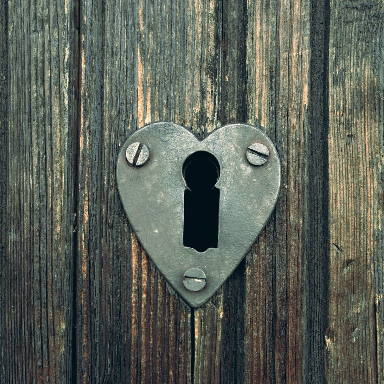 Heart shaped keyhole on rusitc old wooden door.